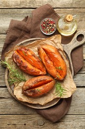 Tasty cooked sweet potatoes with rosemary on wooden table, top view