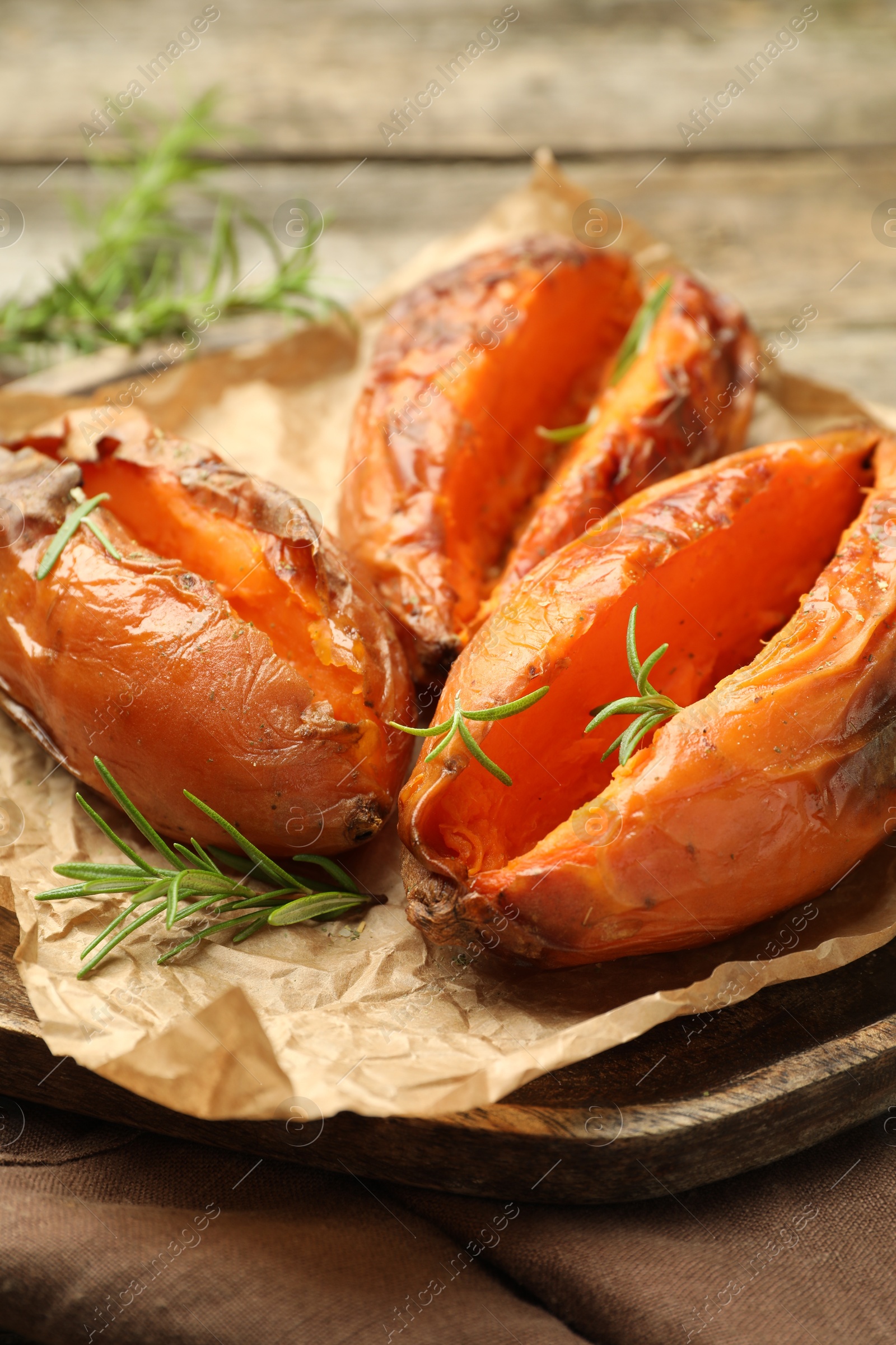 Photo of Tasty cooked sweet potatoes with rosemary on table, closeup