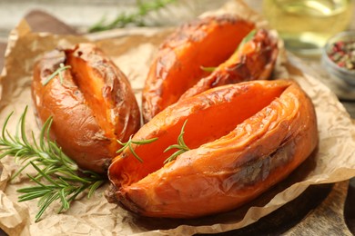 Tasty cooked sweet potatoes with rosemary on table, closeup