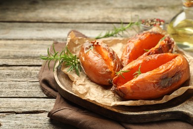 Photo of Tasty cooked sweet potatoes with rosemary on wooden table, closeup