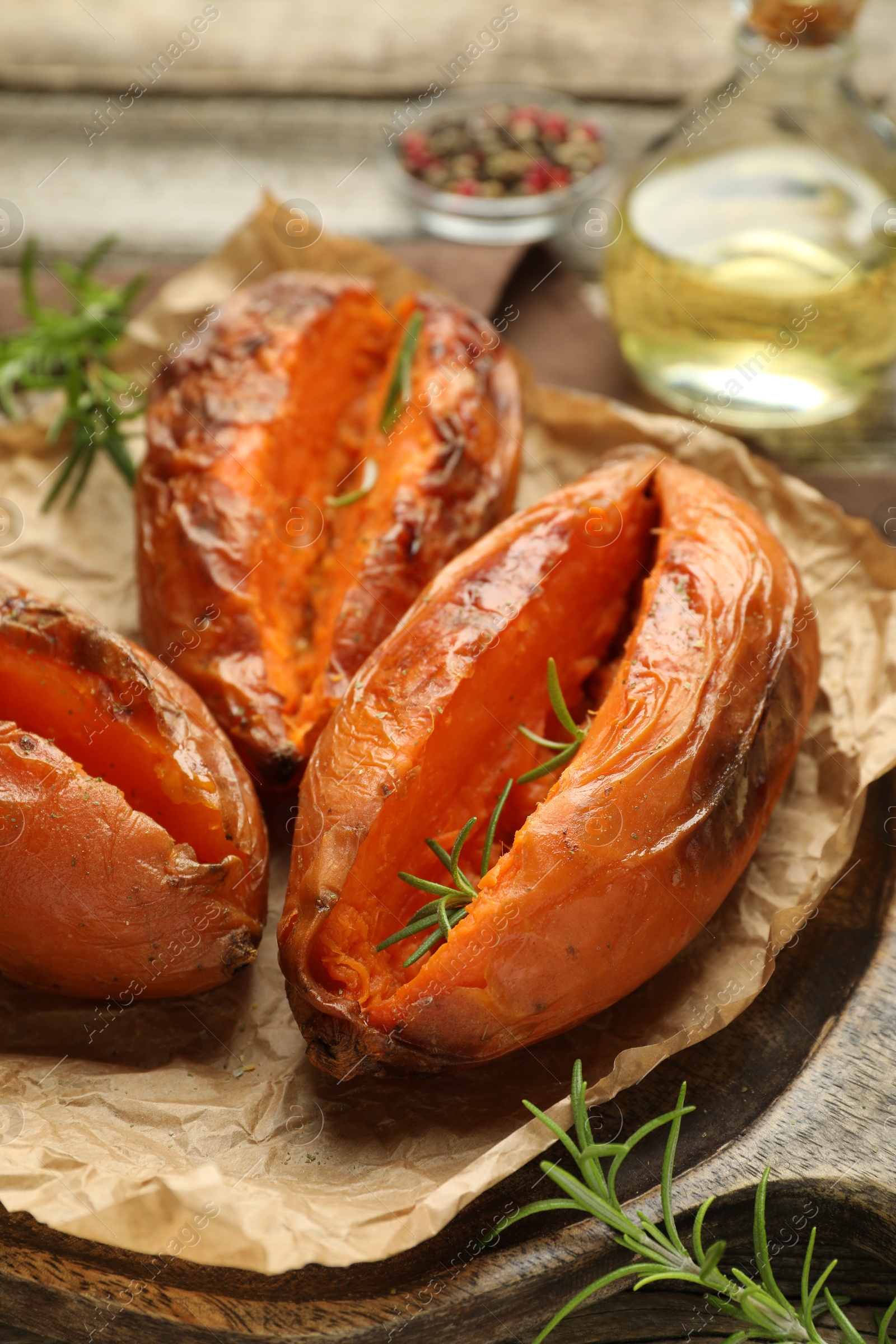 Photo of Tasty cooked sweet potatoes with rosemary on table, closeup