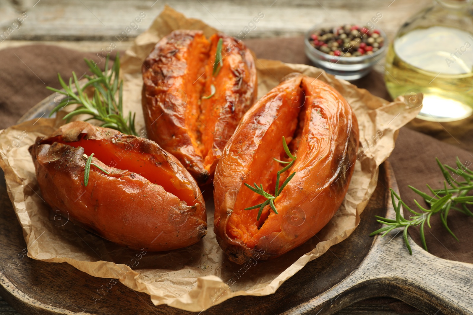 Photo of Tasty cooked sweet potatoes with rosemary on table, closeup