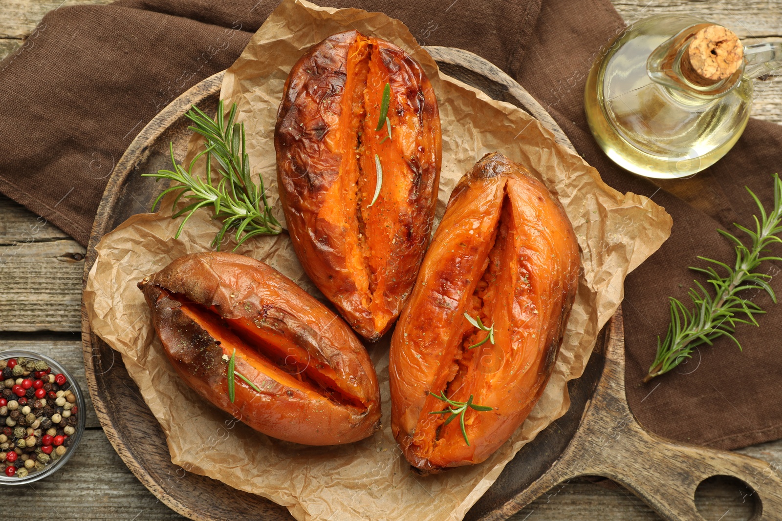 Photo of Tasty cooked sweet potatoes with rosemary on wooden table, top view