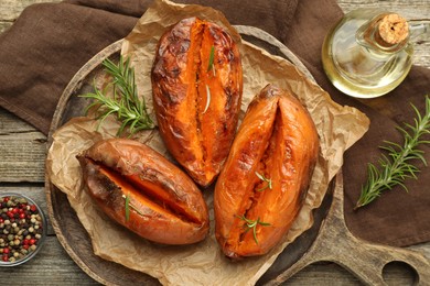 Photo of Tasty cooked sweet potatoes with rosemary on wooden table, top view