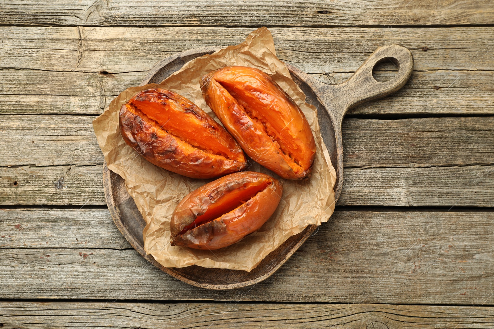 Photo of Tasty cooked sweet potatoes on wooden table, top view