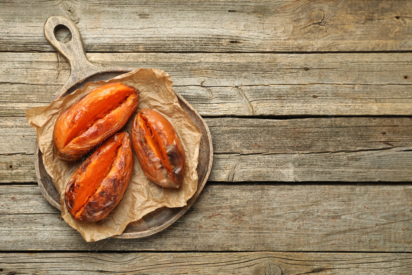 Photo of Tasty cooked sweet potatoes on wooden table, top view. Space for text