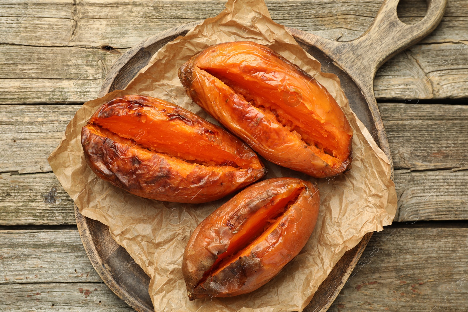 Photo of Tasty cooked sweet potatoes on wooden table, top view