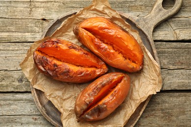 Photo of Tasty cooked sweet potatoes on wooden table, top view