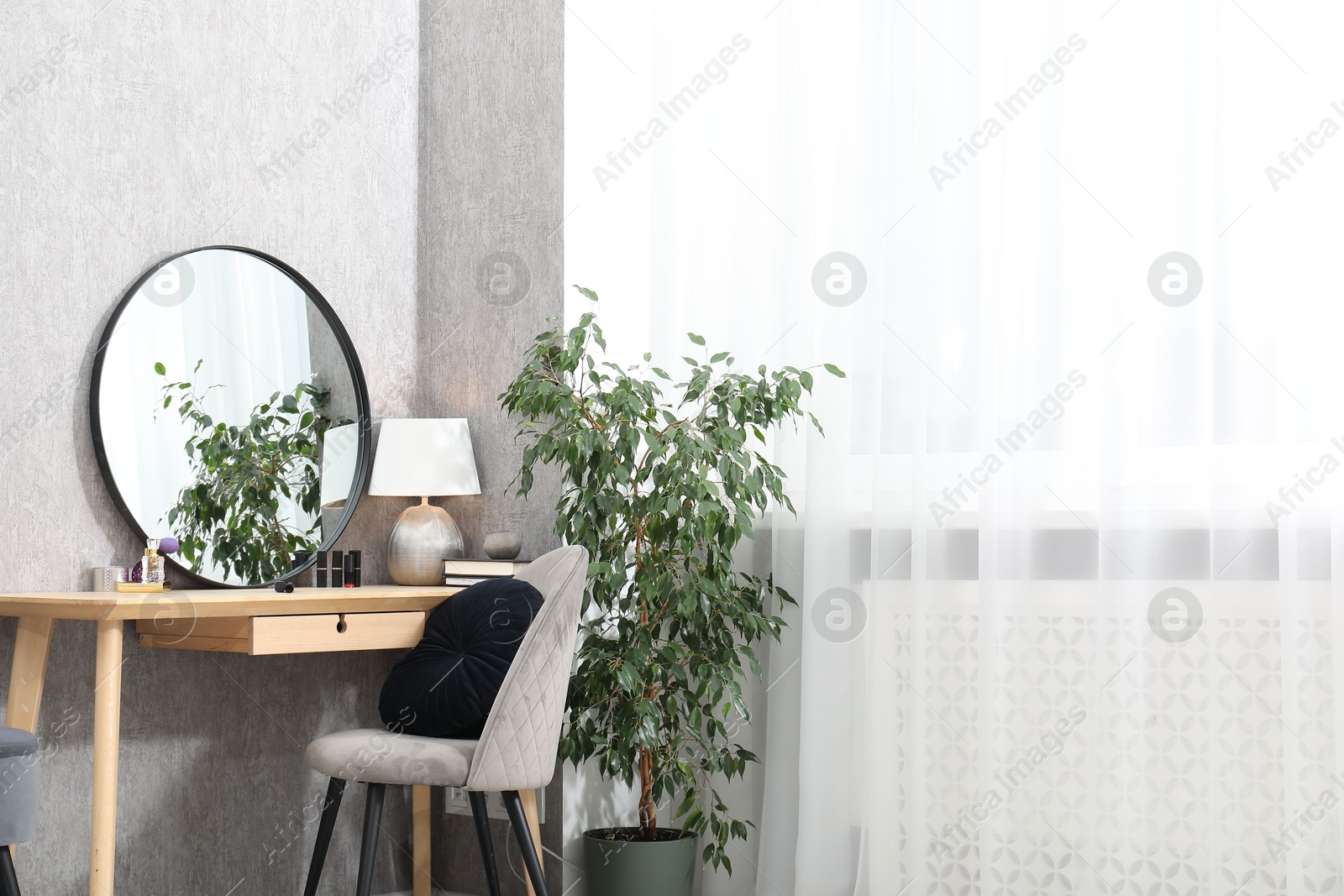 Photo of Mirror, dressing table, lamp, chair and houseplant indoors. Interior design