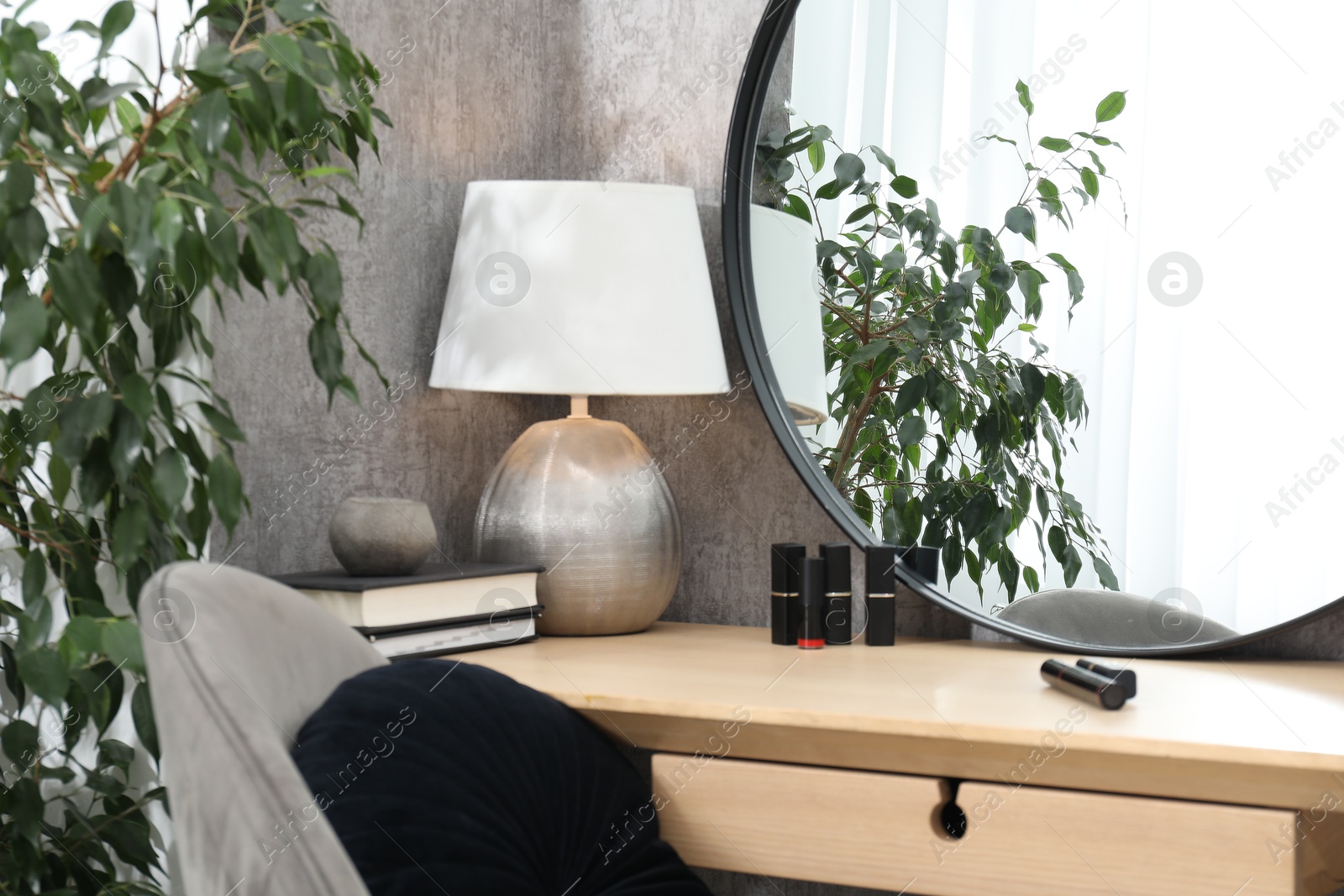 Photo of Mirror, dressing table, lamp, chair and houseplant indoors. Interior design