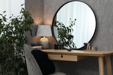 Photo of Mirror, dressing table, lamp, chair and houseplant indoors. Interior design