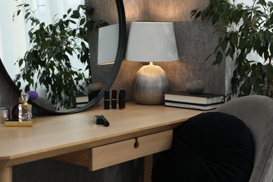 Mirror, dressing table, lamp, chair and houseplant indoors. Interior design