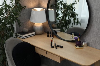 Photo of Mirror, dressing table, lamp, chair and houseplant indoors. Interior design