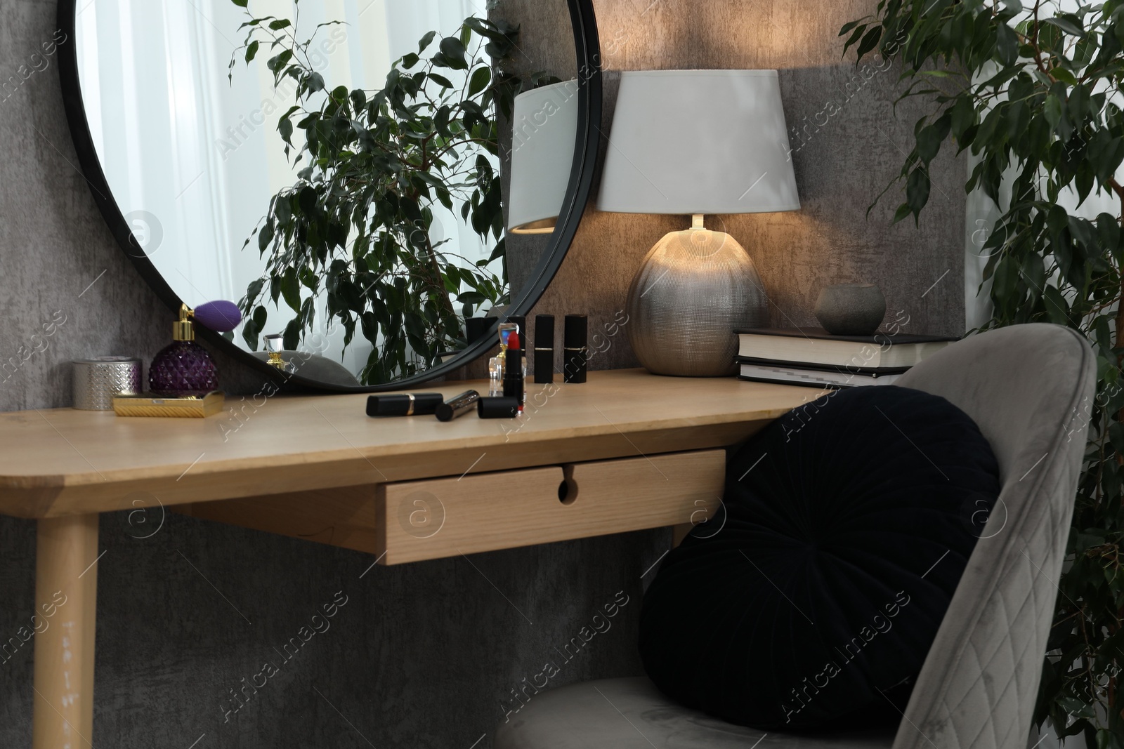 Photo of Mirror, dressing table, lamp, chair and houseplant indoors. Interior design