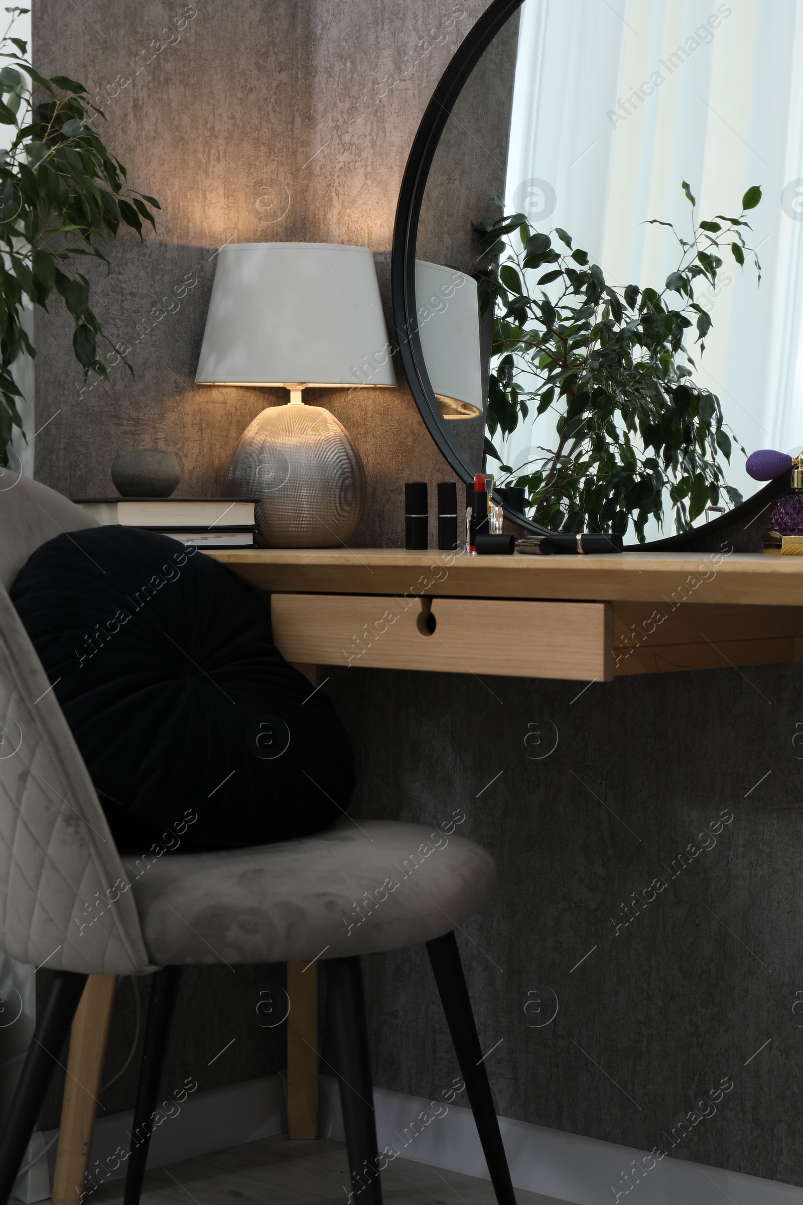 Photo of Mirror, dressing table, lamp, chair and houseplant indoors. Interior design