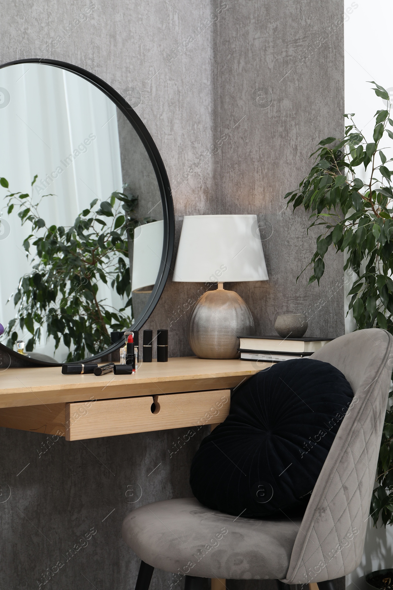 Photo of Mirror, dressing table, lamp, chair and houseplant indoors. Interior design