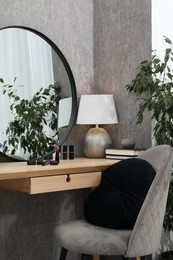 Mirror, dressing table, lamp, chair and houseplant indoors. Interior design