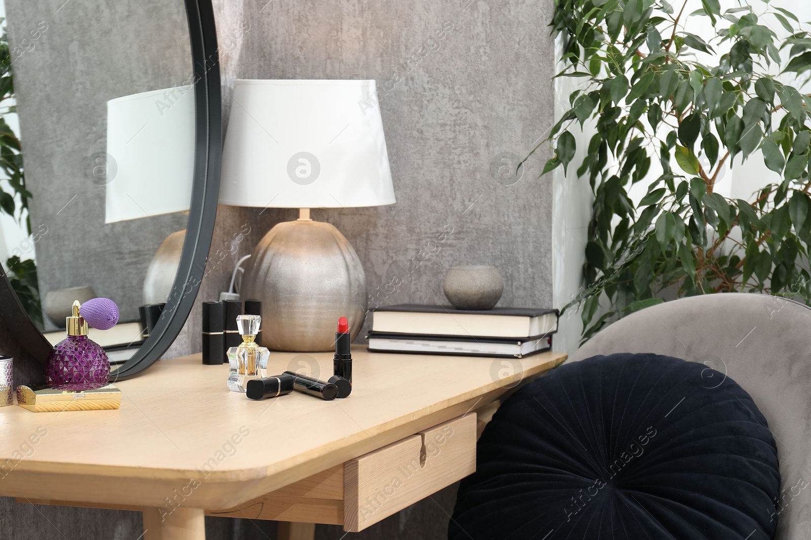 Photo of Mirror, dressing table with cosmetic products, lamp, chair and houseplant indoors. Interior design