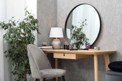 Photo of Mirror, dressing table, lamp, chair and houseplant indoors. Interior design