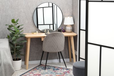 Mirror, dressing table, chair, houseplant and folding screen indoors. Interior design