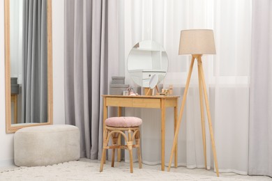 Photo of Mirrors, dressing table, lamp and stool near window indoors. Interior design