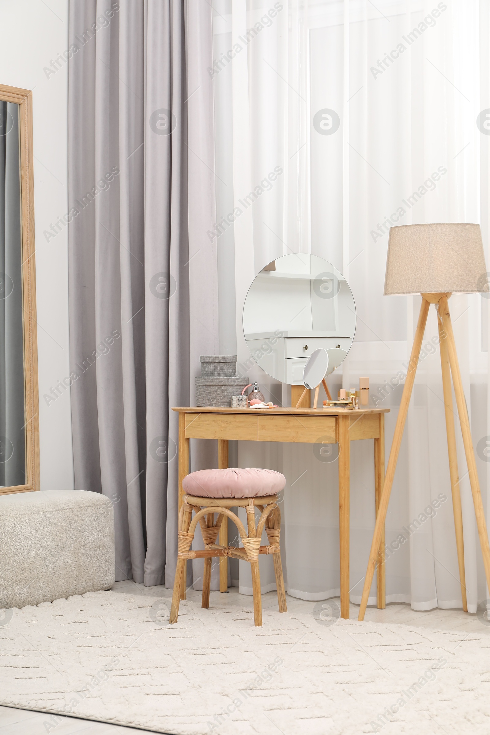 Photo of Mirror, dressing table, lamp and stool near window indoors. Interior design