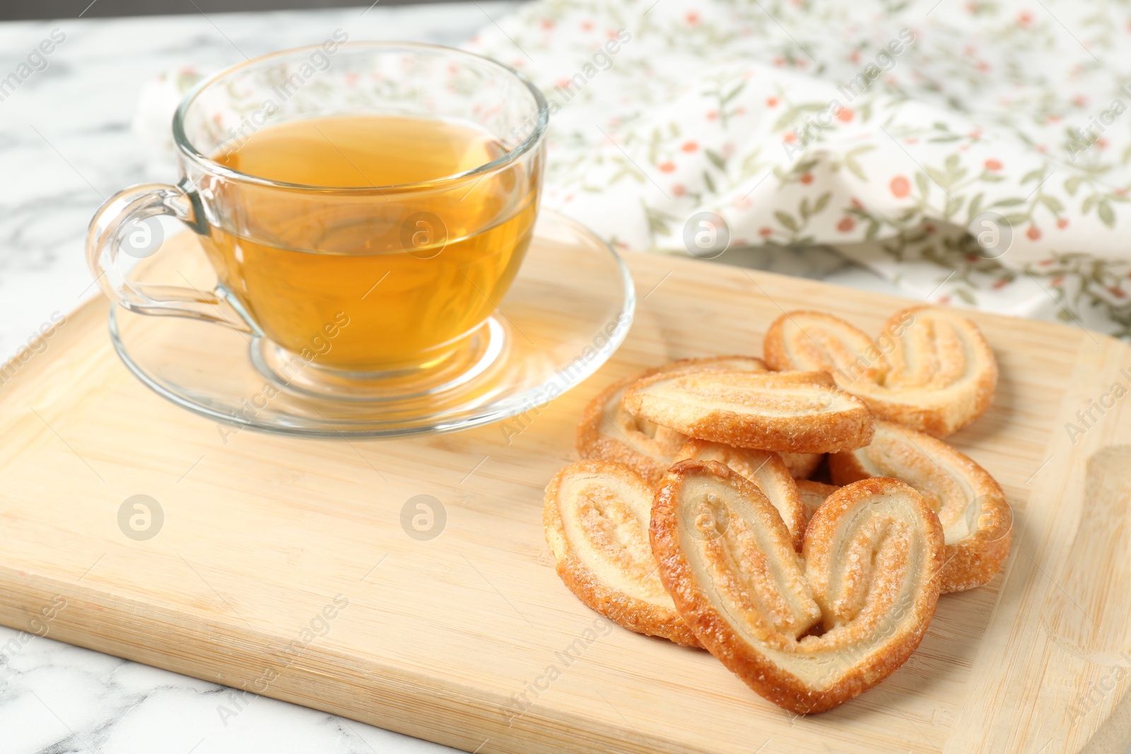 Photo of Delicious palmier cookies with tea on white table, closeup