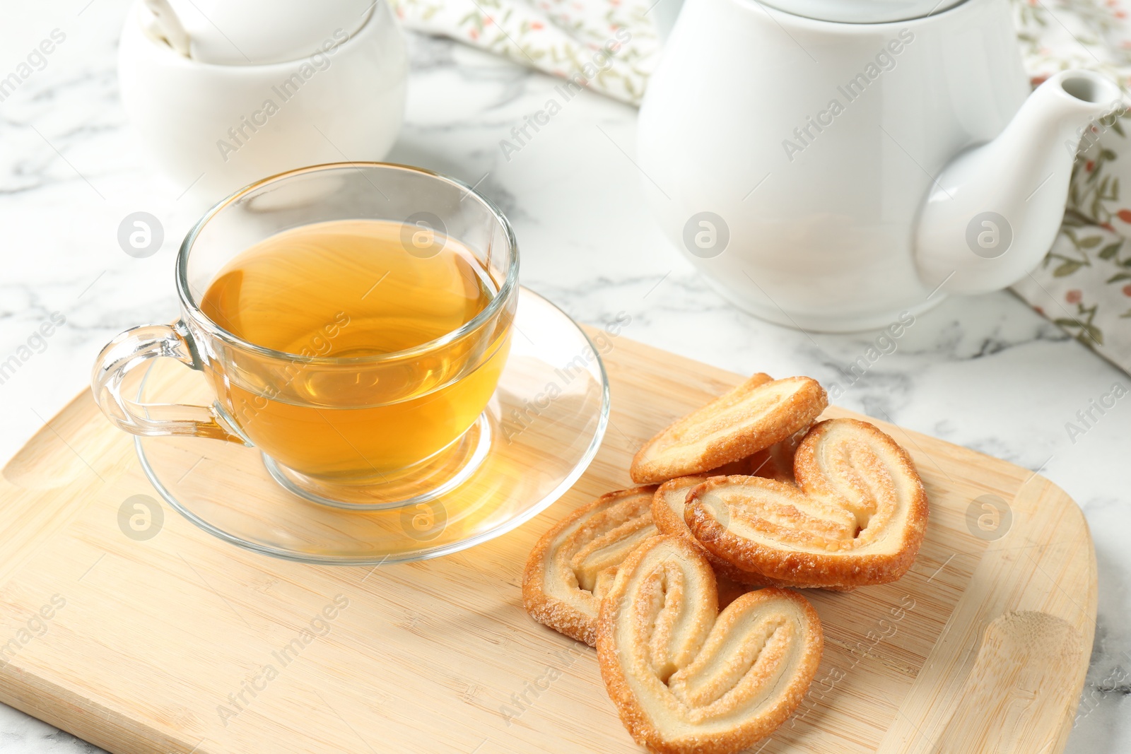 Photo of Delicious palmier cookies with tea on white table, closeup