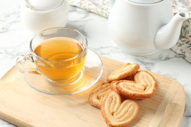 Delicious palmier cookies with tea on white table, closeup