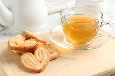 Photo of Delicious palmier cookies with tea on white table, closeup