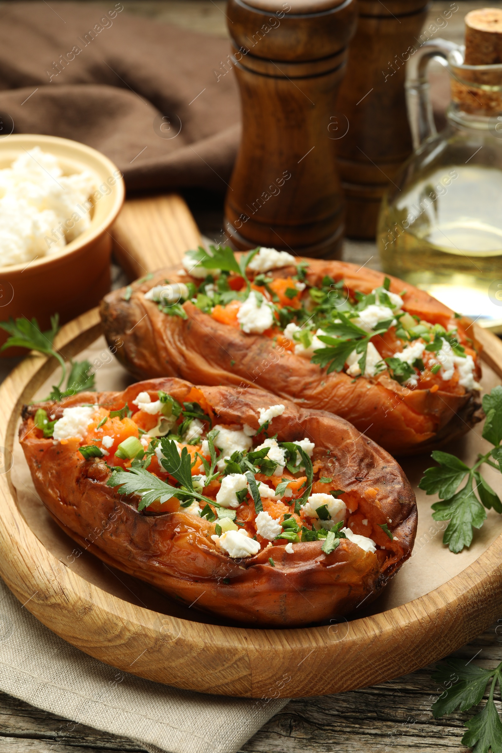 Photo of Tasty cooked sweet potatoes with feta cheese, green onion and parsley on table, closeup