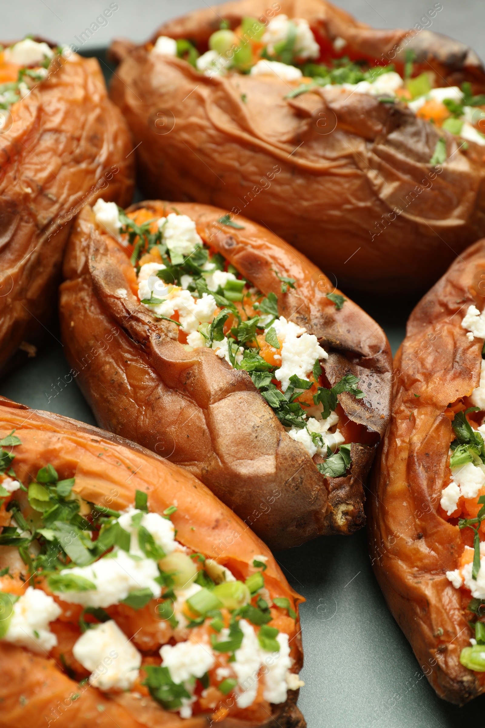 Photo of Tasty cooked sweet potatoes with feta cheese, green onion and parsley on plate, closeup