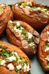 Tasty cooked sweet potatoes with feta cheese, green onion and parsley on plate, closeup