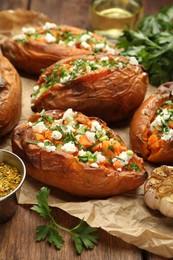 Photo of Tasty cooked sweet potatoes with feta cheese, green onion and parsley on wooden table, closeup