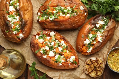 Photo of Tasty cooked sweet potatoes with feta cheese, green onion, spices and oil on table, top view