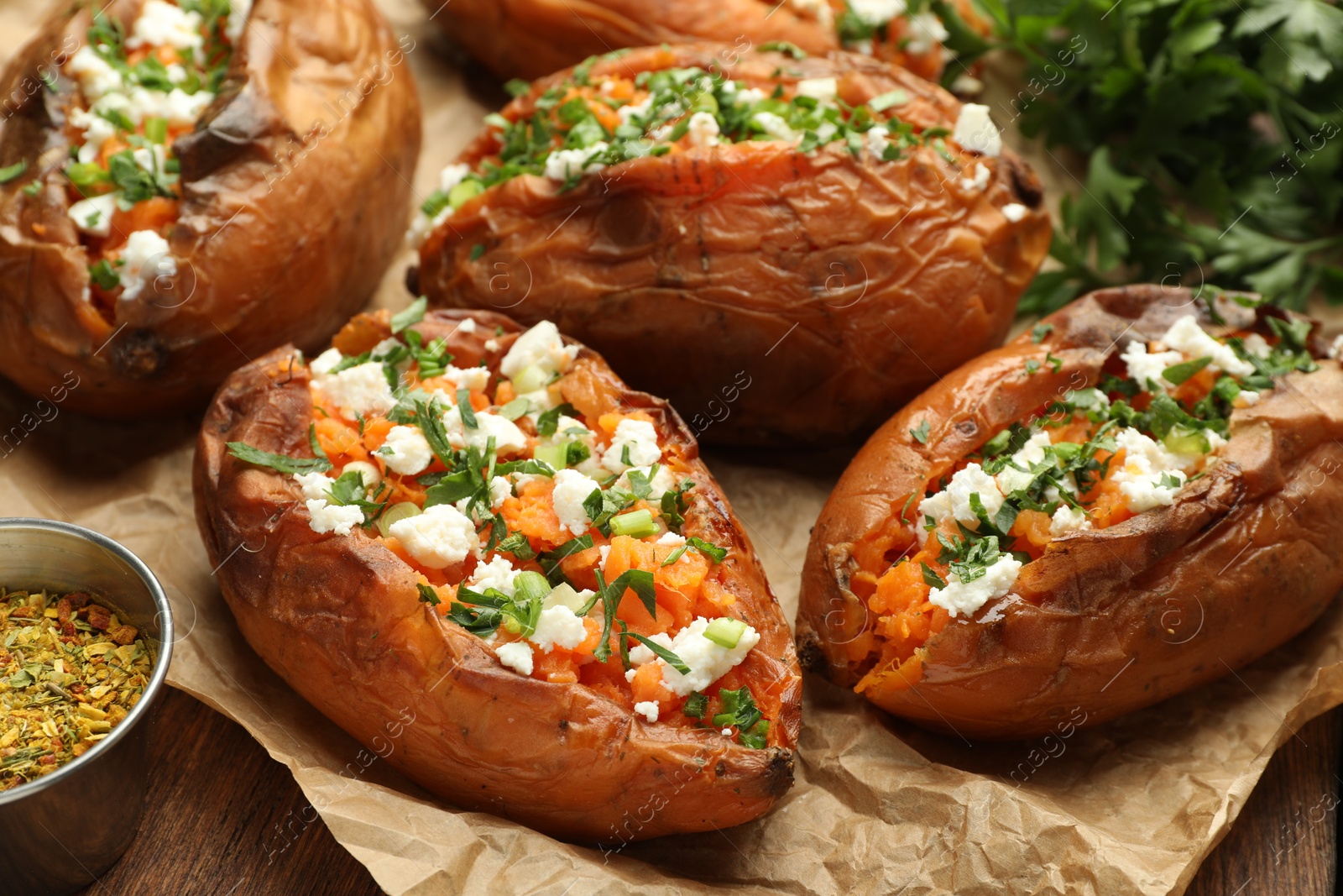 Photo of Tasty cooked sweet potatoes with feta cheese, green onion and parsley on table, closeup