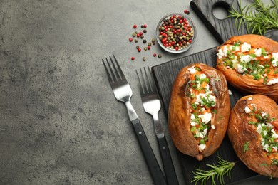 Photo of Tasty cooked sweet potatoes with feta cheese, green onion and parsley served on gray textured table, flat lay. Space for text