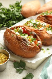 Photo of Tasty cooked sweet potatoes with feta cheese, green onion and parsley on table, closeup