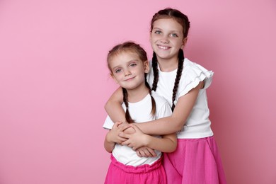 Photo of Portrait of cute little sisters on pink background, space for text