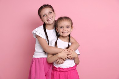 Photo of Portrait of cute little sisters on pink background