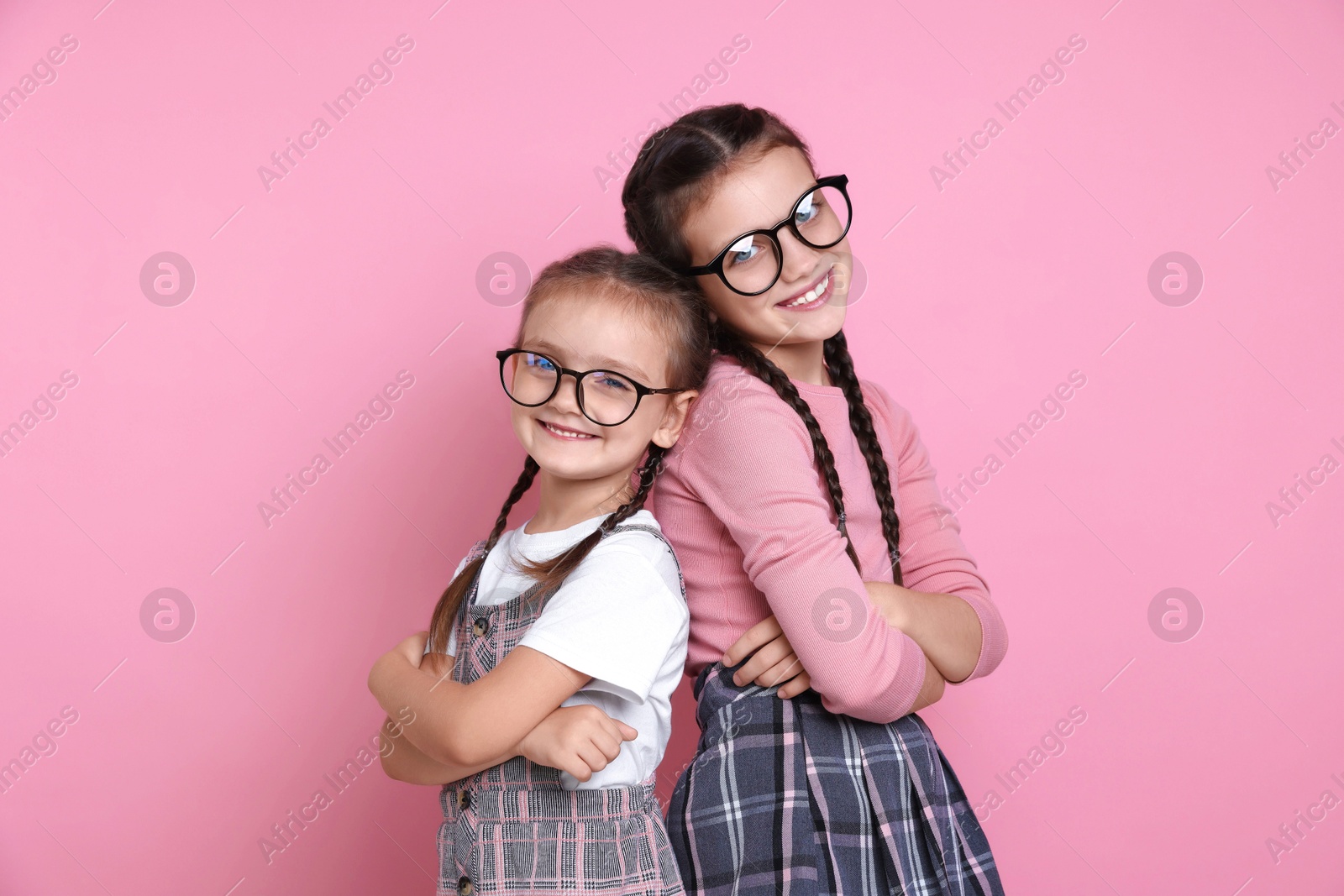 Photo of Portrait of cute little sisters on pink background