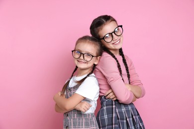 Portrait of cute little sisters on pink background