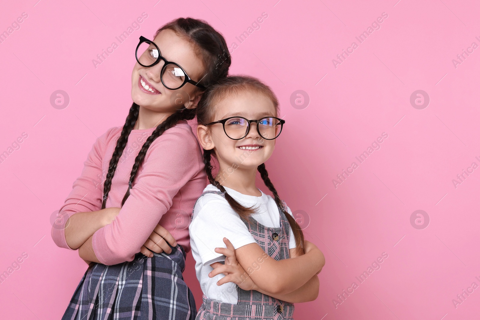 Photo of Portrait of cute little sisters on pink background