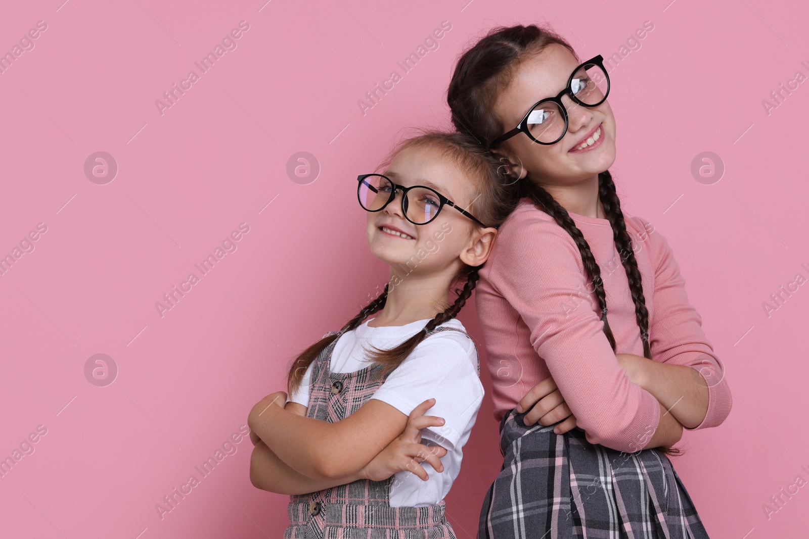 Photo of Portrait of cute little sisters on pink background