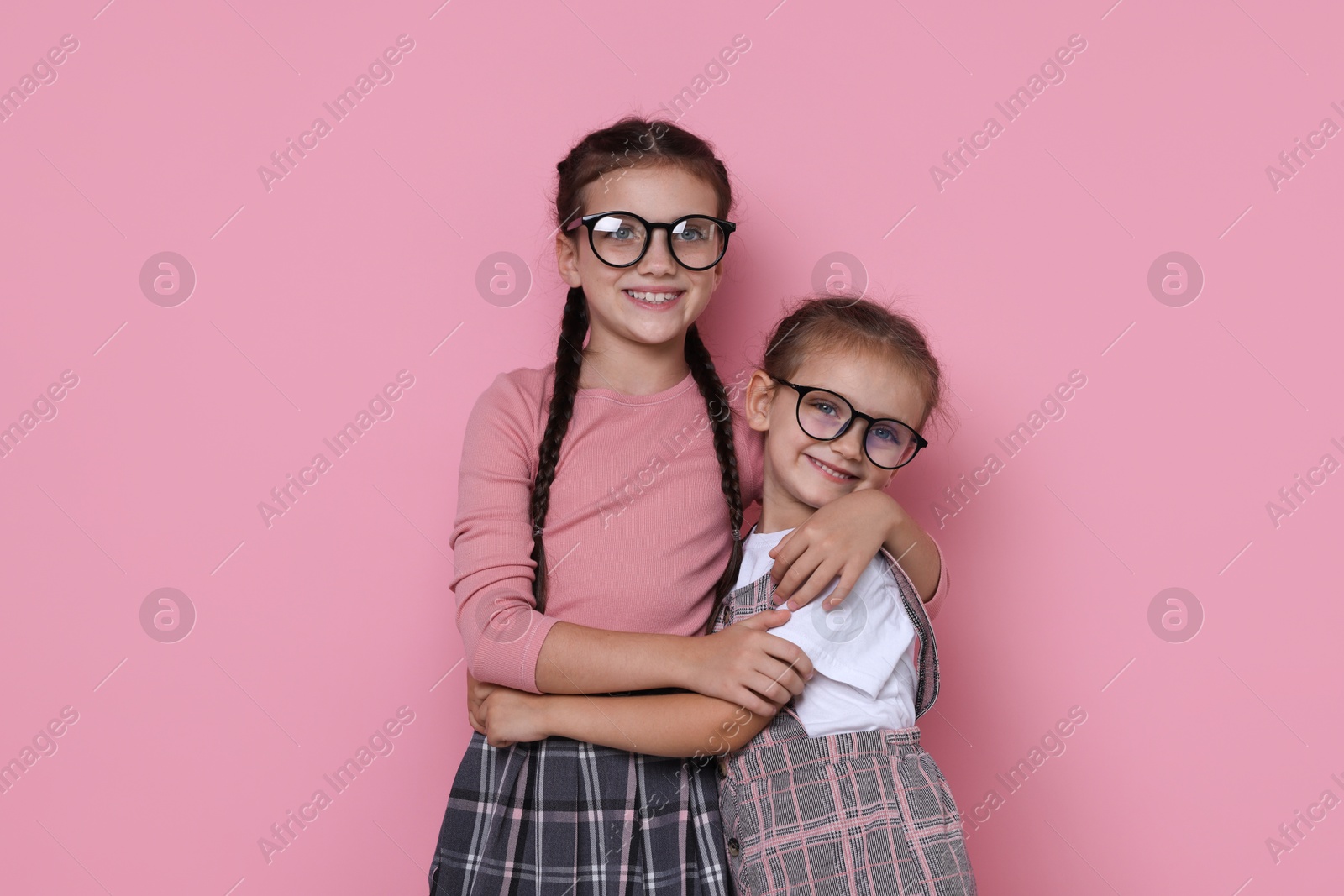 Photo of Portrait of cute little sisters on pink background