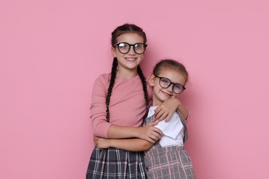 Portrait of cute little sisters on pink background