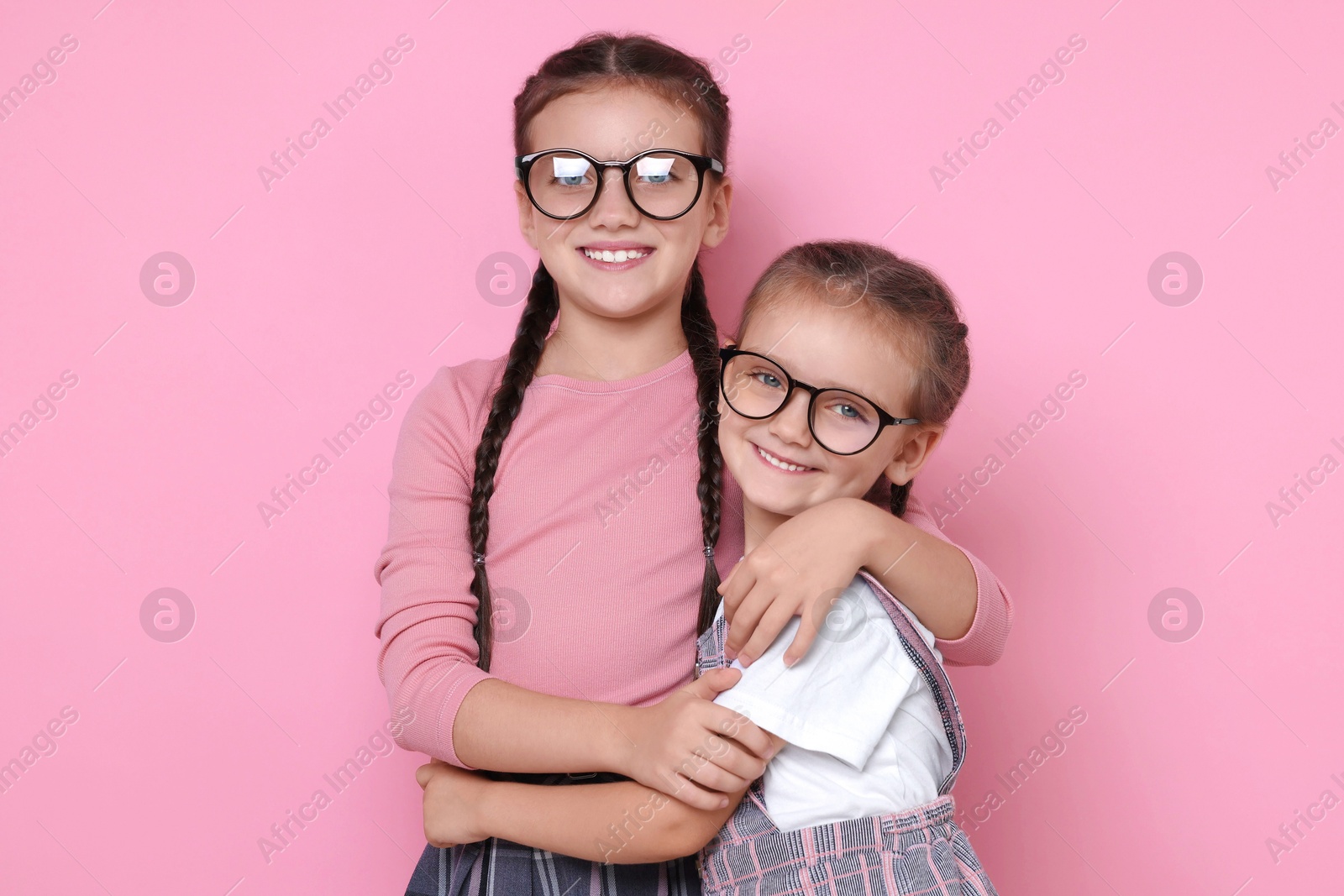 Photo of Portrait of cute little sisters on pink background