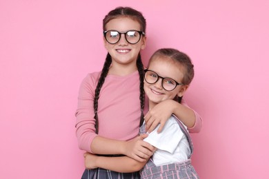 Portrait of cute little sisters on pink background