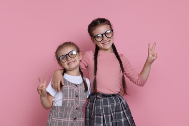 Portrait of cute little sisters on pink background