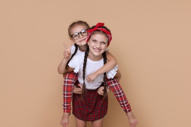 Portrait of cute little sisters on beige background